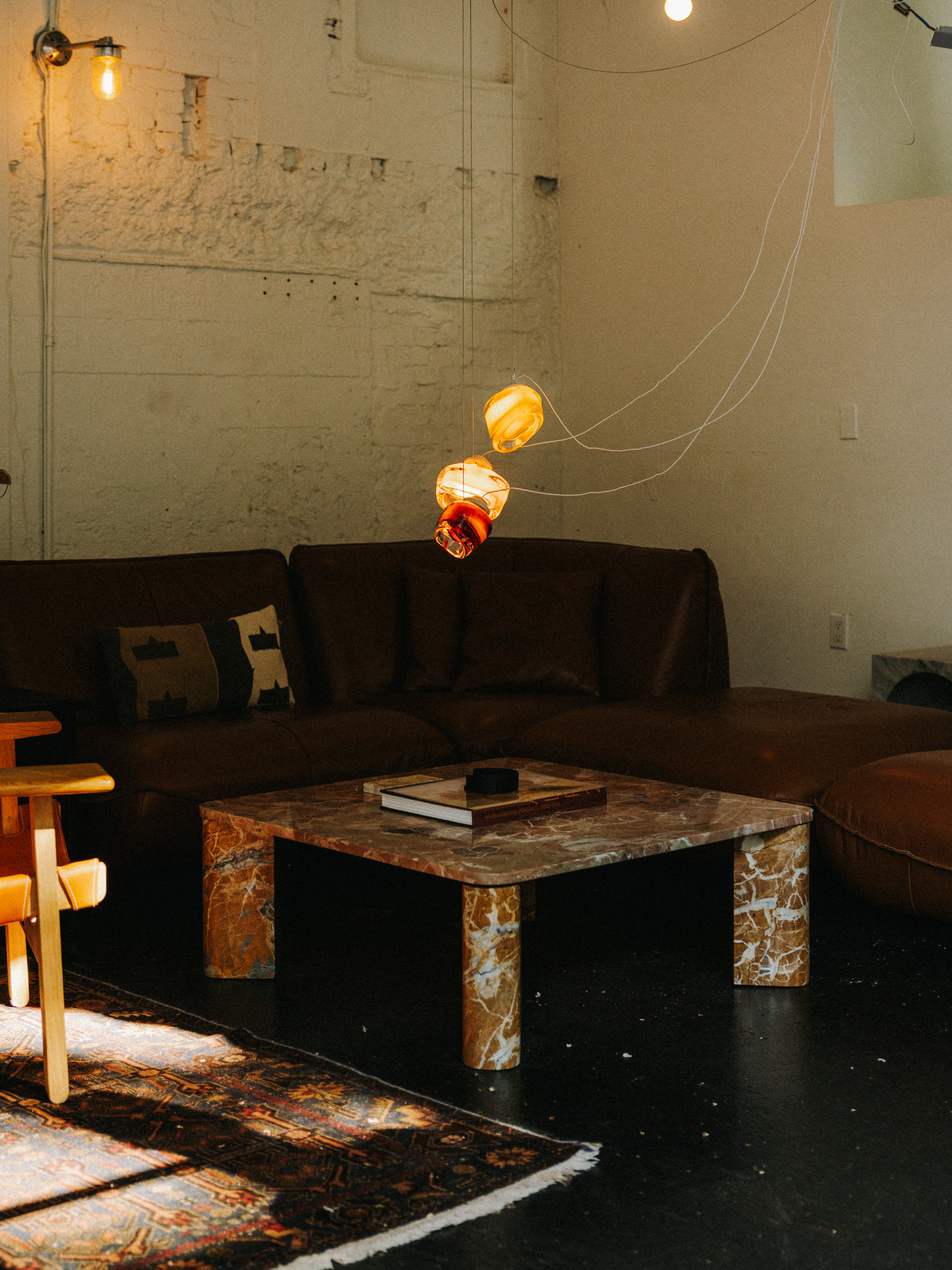 The Barnacle cluster lit low over the studio lounge — leather sofas, marble table, warm light